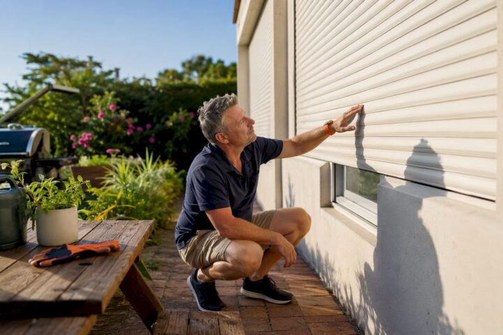 Homeowner inspecting external roller shutters outside house