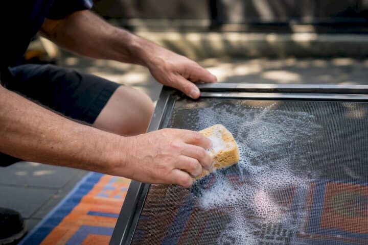 Hands cleaning security screen mesh with sponge